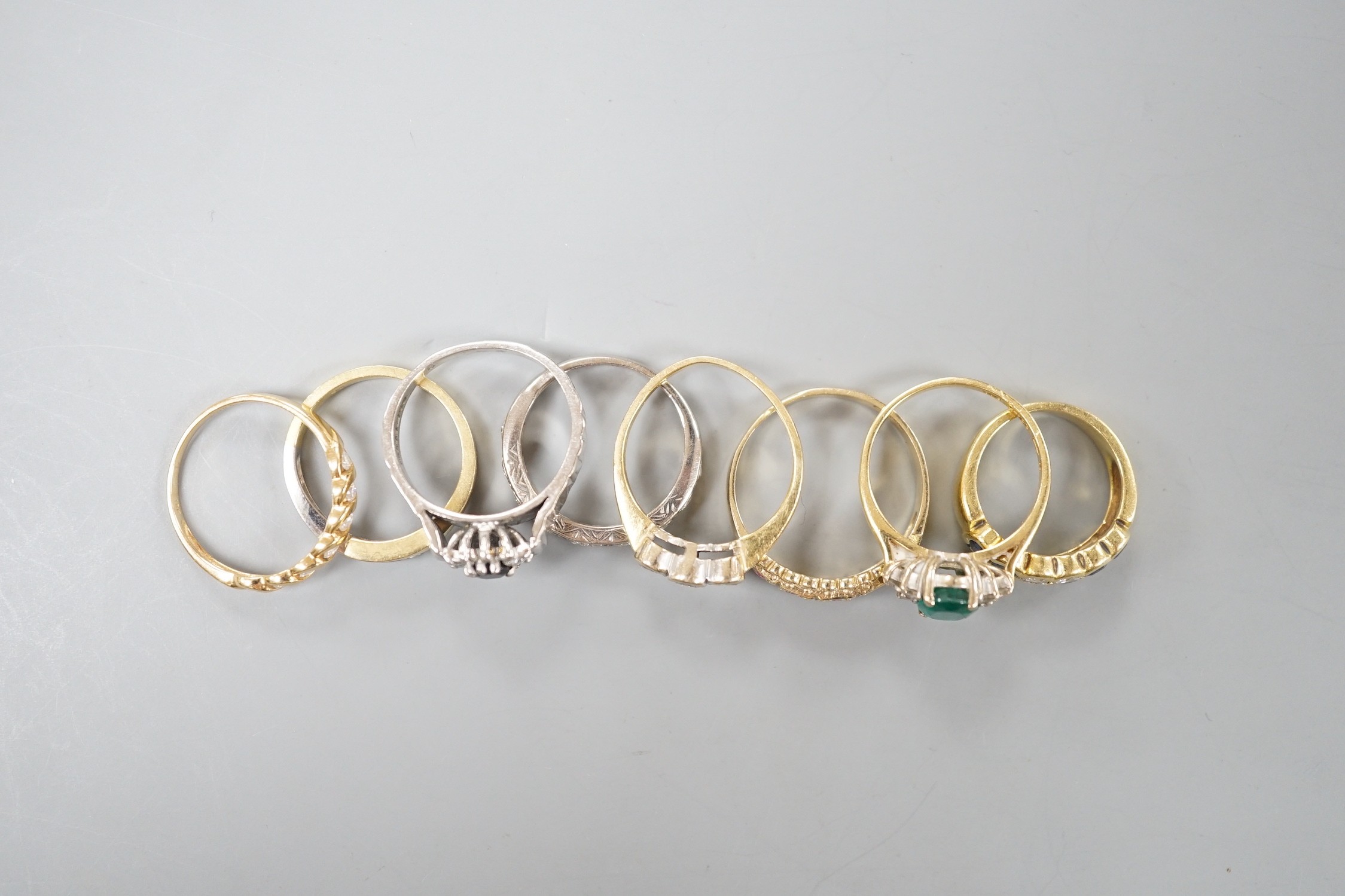 Seven assorted mainly modern 18ct gold or 750 yellow metal and gem set dress rings including emerald and diamond and diamond half eternity, gross weight 26 grams and one 9ct gold and gem set ring, gross 2.9 grams.